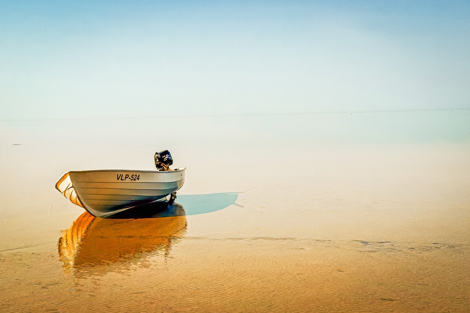A lone boat resting on still water in golden light